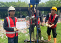 Tiga pekerja teknis Khandaq dengan helm dan rompi keselamatan sedang melakukan uji sondir tanah menggunakan alat mekanis di lokasi proyek Kalideres, memegang papan identifikasi bertuliskan Sondir TS 01.